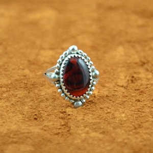 Peut inclure: Une bague en argent avec une pierre ovale rouge sertie dans une bélière perlée.