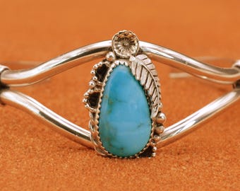 May include: A silver bracelet with a turquoise stone set in a silver leaf design.
