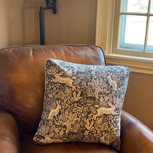 May include: A brown leather armchair with a throw pillow featuring a white and black pattern of rabbits and flowers.