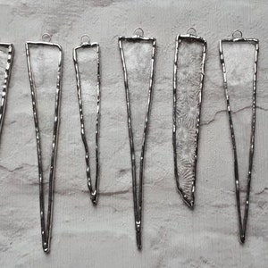 以下が含まれることがあります： 先が尖っていて、上部に吊り下げ用のループが付いた、銀色のガラス製のつららオーナメントが8個です。