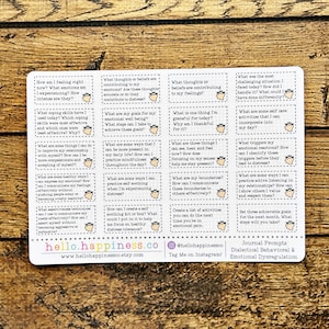 Puede incluir: Una hoja de pegatinas blanca con indicaciones de diario para el comportamiento dialéctico y la desregulación emocional. Las indicaciones están en pequeños cuadros rectangulares con un pequeño icono de planta.