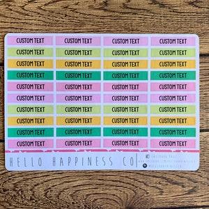 May include: A sheet of colorful custom text labels with a pink, yellow, green, and light blue color scheme. The labels are rectangular and have rounded corners. The text "CUSTOM TEXT" is printed on each label. The bottom of the sheet has the text "HELLO HAPPINESS CO."