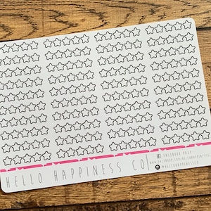 Puede incluir: Una hoja de papel adhesivo blanco con 100 pegatinas de estrellas de contorno negro. La hoja tiene el texto "HELLO HAPPINESS CO" impreso en la parte inferior. El texto "FACEBOOK PAGE" est&aacute; impreso en la esquina inferior derecha.