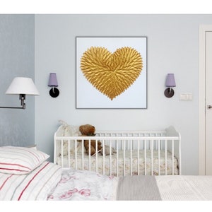 May include: A square wall art piece featuring a textured, three-dimensional golden heart shape composed of numerous small, leaf-like elements arranged in a radial pattern, set against a plain white background within a thin, dark frame.