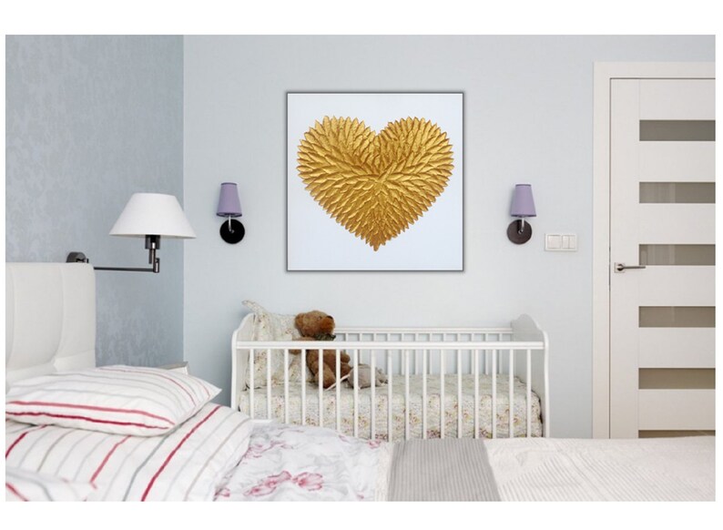 May include: A square wall art piece featuring a textured, three-dimensional golden heart shape composed of numerous small, leaf-like elements arranged in a radial pattern, set against a plain white background within a thin, dark frame.