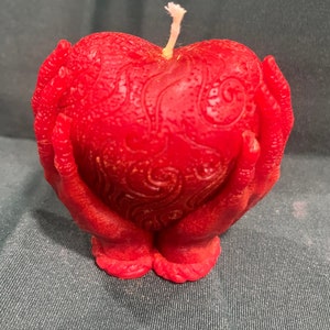 Manos sosteniendo una vela en forma de corazón