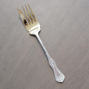May include: A silver cake fork with a gold-plated tines and an ornate handle.