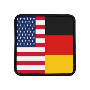 Könnte beinhalten: Ein schwarzer Patch mit einem aufgenähten Bild der amerikanischen und der deutschen Flagge nebeneinander.
