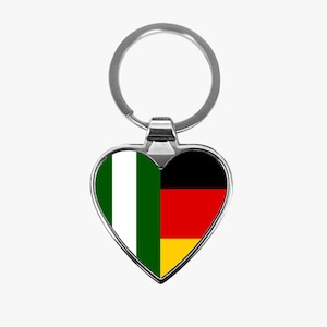 May include: A silver heart-shaped keychain with the flags of Nigeria and Germany on it.