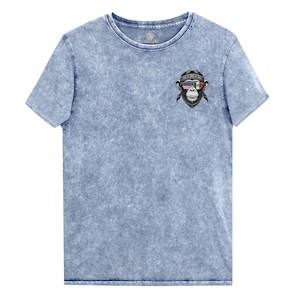 Peut inclure: Un t-shirt bleu clair à l'aspect vieilli avec un singe portant des lunettes de soleil avec les drapeaux américain et mexicain. Le singe porte un bandana avec le mot "BORO" dessus.