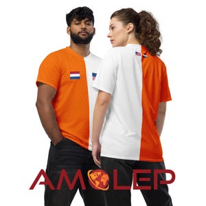 May include: Two people wearing orange and white t-shirts with the American and Dutch flags on them. The shirts are split down the middle, with one side orange and the other white.