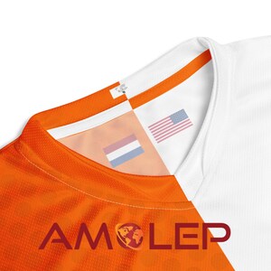 May include: Orange and white football shirt with the American and Dutch flags on the collar. The shirt has the word "AMOLEP" printed on the front.