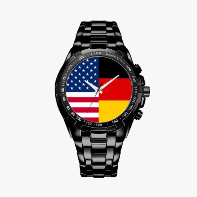May include: Black wristwatch with a black band and a face featuring the American and German flags. The watch face also has a tachymeter scale.