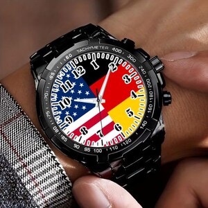 May include: A black wristwatch with a tachymeter bezel and a face featuring the flags of the United States and Germany. The watch has a black leather band.