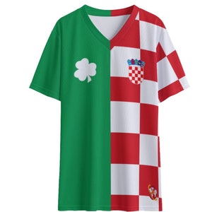 May include: A green and white t-shirt with a shamrock on the left side and a checkered red and white pattern on the right side. The right side also features a crest with a checkered shield and a crown.