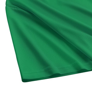 May include: A close-up of a green fabric with a textured surface. The fabric is folded and has a smooth, even texture.