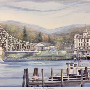 May include: A watercolor painting depicting a view of East Haddam, Connecticut. The painting features a wooden bridge over a river, a white building with a tower, a small boat docked at a pier, and a mountain range in the background.