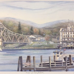 May include: A watercolor painting of a view of East Haddam, Connecticut. The painting features a wooden bridge, a white building with a tower, a boat docked at a pier, and a mountain range in the background.