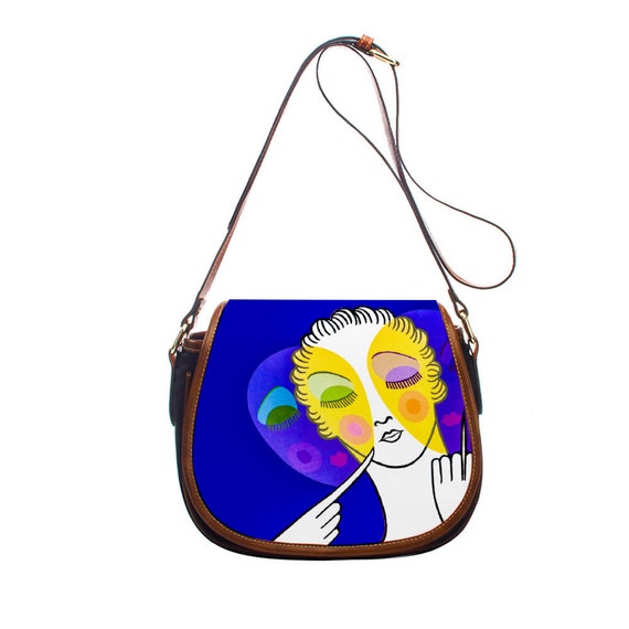 Small graceful elegant art deco shoulder bag, inspired by the aristocratic Erte. Face and mask, happiness y sadness on a purple background