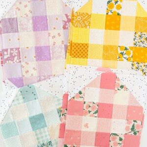 Quilt squares in pink, yellow, purple, and teal patterns are neatly arranged, each featuring floral and checkered designs on a speckled white background.