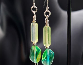 May include: A pair of silver dangle earrings with green and yellow glass beads. The beads are faceted and have a translucent appearance.