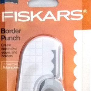 May include: Orange and white Fiskars border punch with a scalloped edge design. The packaging features the Fiskars logo and the text "Border Punch".