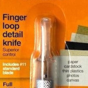 May include: A Fiskars finger loop detail knife with a silver blade and a yellow handle. The packaging includes the text "Fiskars World's #1 Scissors Brand" and "Finger loop detail knife Superior control Includes #11 standard blade Full Lifetime Warranty". The packaging also lists the materials the knife can cut: paper, cardstock, thin plastics, photos, and canvas.