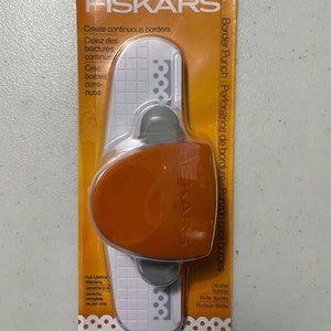 May include: Orange and white Fiskars border punch with a scalloped edge design. The packaging features the text "Create continuous borders" and "Border Punch Perforatrice de bordure Punzón para bordes".