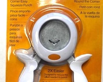 May include: White corner rounder punch with orange accents. The packaging features the Fiskars logo and the text "Corner Easy Squeeze Punch" and "Round the Corner".