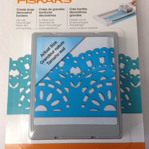 May include: A close-up of a Fiskars AdvantEdge large cartridge for creating decorative borders. The cartridge is shown with a sample of the design it creates, a blue lace pattern. The text "Actual Size" is printed on the cartridge. The text "Large cartridge" is printed on the packaging.