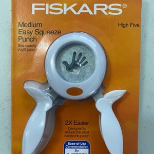 May include: White Fiskars Easy Squeeze Punch with a hand-shaped cutout. The packaging features the text "High Five" and "2X Easier". It also includes an Arthritis Foundation Ease-of-Use Commendation.