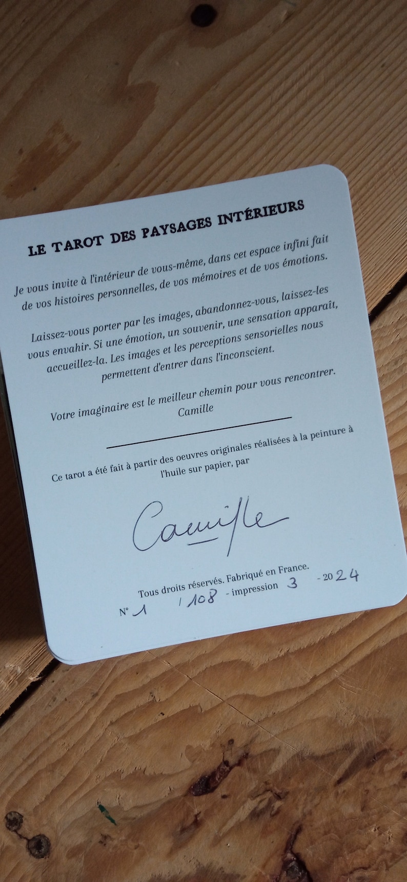 May include: A blue card with the title "Le Tarot des Paysages Int&eacute;rieurs" and text in French about the tarot deck. The card also includes the signature "Camille" and the number "1/108" printed on the bottom.