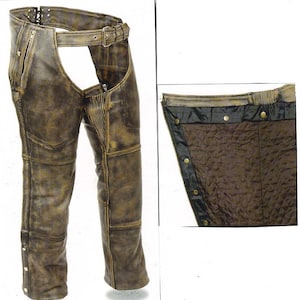 May include: Distressed brown leather chaps with a zipped front and a belt loop. The chaps have a snap closure on the side and a decorative stitching detail.