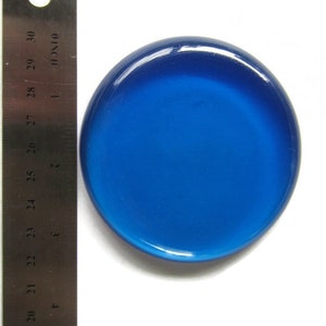 May include: A round, blue glass paperweight with a smooth, glossy finish. The paperweight is approximately 5 cm in diameter.