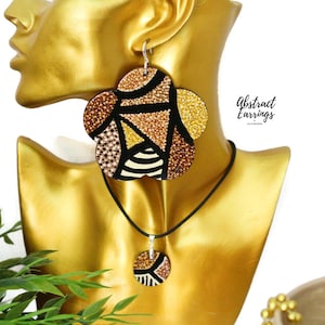May include: A gold and black geometric patterned necklace and earrings set. The earrings are large and round, while the pendant is smaller and round. The jewelry is made of wood and has a shiny finish.