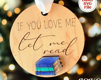 May include: A round wooden ornament with a white ribbon hanger. The text IF YOU LOVE ME let me read is engraved in black. Below the text is a small, three-dimensional stack of three books in blue and teal colors with visible page edges.