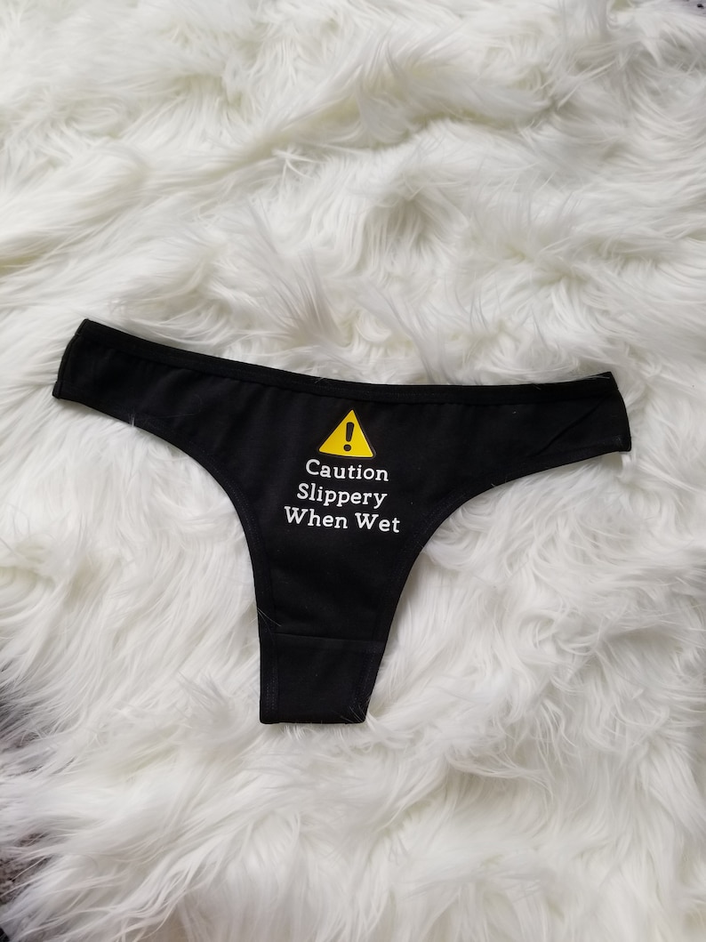 Another flat lay from further away of the cautions slippery when wet design on a black thong.