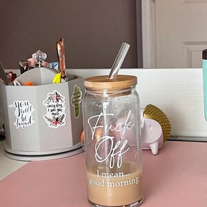 Customer photo of a 20oz cup with white text sitting on a desk with a bamboo lid and glass bent straw.