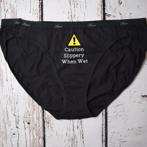 Caution slippery when wet design shown on a black bikini style underwear.
