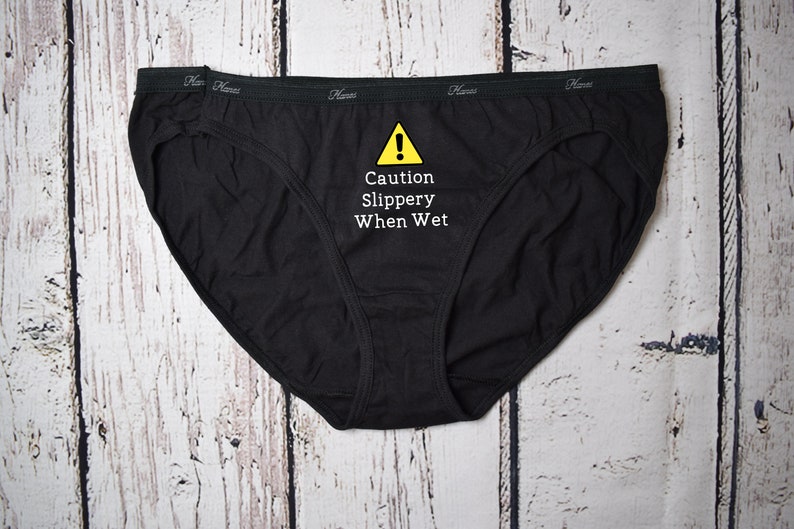 Caution slippery when wet design shown on a black bikini style underwear.