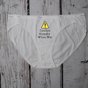 Caution slippery when wet design shown on a white bikini style underwear.