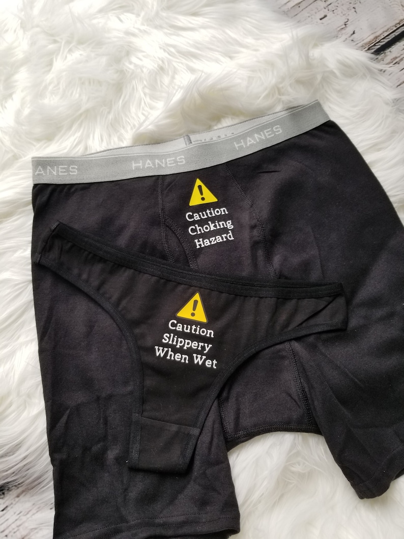 May include: Black underwear with a yellow warning sign that says "Caution Choking Hazard" on the waistband and "Caution Slippery When Wet" on the front.