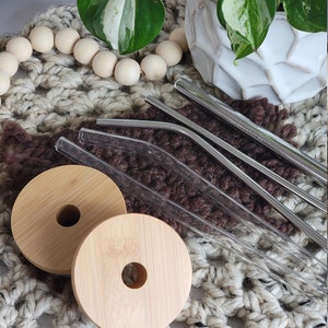 Bamboo lids shown with a slight sheen showing the water resistant finish. Available straws shown are glass straight or bent, stainless steel straight or bent, and stainless steel boba/bubble tea straw.