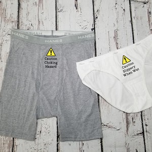Matching boxer briefs and bikini underwear with saying on front. Men's says caution choking hazard, women's says caution slippery when wet. Women's comes in black or white thong or bikini, men's comes in black or grey boxer briefs.