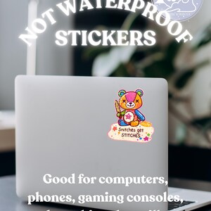 K&ouml;nnte beinhalten: Ein Laptop mit einem bunten Aufkleber eines B&auml;ren, der ein Messer h&auml;lt, mit dem Text "Snitches get STITCHES". Die Worte "NOT WATERPROOF STICKERS" stehen &uuml;ber dem Laptop. Der Text darunter lautet "Good for computers, phones, gaming consoles, and anything that will not get wet!"