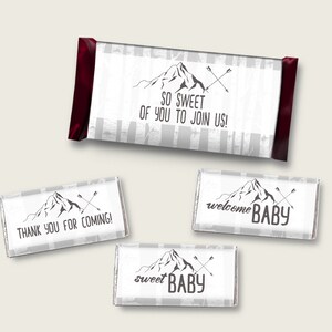 Könnte beinhalten: Vier weiße Schokoladenriegel-Verpackungen mit einem Berg- und Pfeil-Design. Die Verpackungen haben den Text "SO SWEET OF YOU TO JOIN US!", "THANK YOU FOR COMING!", "sweet BABY" und "welcome BABY".