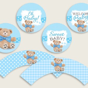 May include: Blue and white cupcake wrappers with a teddy bear design. The wrappers have polka dots and gingham patterns. The teddy bear is wearing a blue bow tie. The cupcake wrappers are perfect for a baby shower.