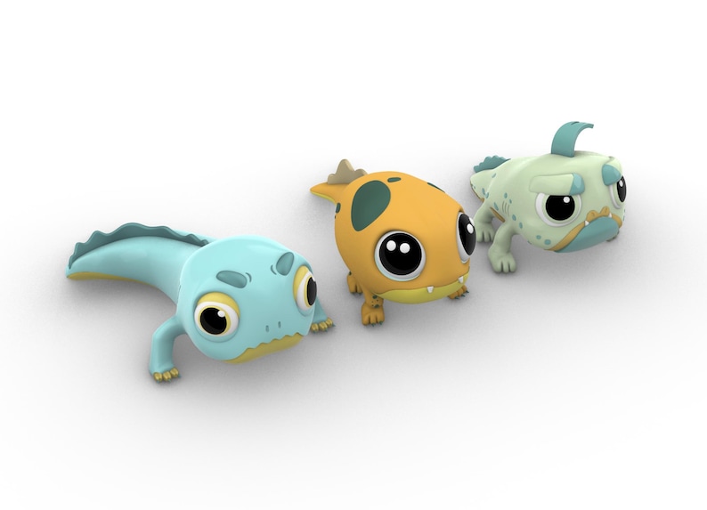 Pu&ograve; includere: Tre figurine di stile cartone animato di piccole creature colorate con occhi grandi ed espressioni espressive. Le creature hanno la forma di lucertole o salamandre e hanno code lunghe. La prima creatura &egrave; blu chiaro con la pancia gialla, la seconda &egrave; arancione con macchie nere e la terza &egrave; verde chiaro con la pancia gialla.