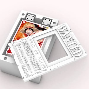 Könnte beinhalten: Eine weiße Vitrine mit zwei Würfeln und einer Karte mit einer Cartoonfigur mit Strohhut. Ein weißer Rahmen mit dem Wort "WANTED" und ein "DEAD OR ALIVE"-Poster mit dem Namen "MONKEY D. LUFFY" sind ebenfalls vorhanden.