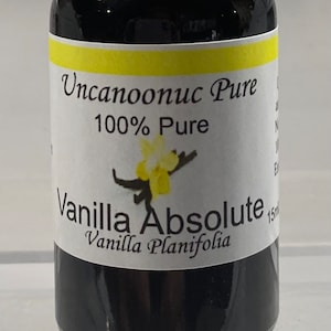 May include: A dark glass bottle with a black dropper top. The label reads "Uncanoonuc Pure 100% Pure Vanilla Absolute Vanilla Planifolia". The bottle contains 15 ml of liquid.